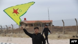 FILE - A Syrian Kurd waves the flag of YPG (People's Protection Units) near Qamishli's airport in northeastern Syria on December 8, 2024, following the fall of the capital Damascus to anti-government fighters.