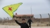 Un kurdo sirio ondea la bandera de las YPG (Unidades de Protección Popular) cerca del aeropuerto de Qamishli, en el noreste de Siria, el 8 de diciembre de 2024, tras la caída de la capital, Damasco, ante combatientes antigubernamentales.