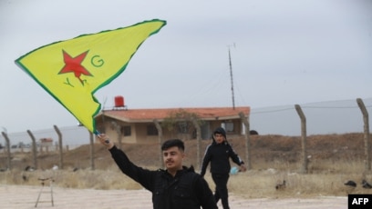 A Syrian Kurd waves the flag of the YPG (People's Protection Units) near Qamishli airport in northeastern Syria on December 8, 2024, after the fall of the capital Damascus to anti-government fighters.