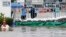FILE - Workers look on behind flood protection barriers built at their factory at Amata Nakorn industrial Estate in Chonburi province, east of Bangkok, Oct. 9, 2013.