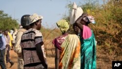 In this photo taken Dec. 7, 2018, women and girls speak to members of a UN peacekeeping patrol as they walk to get food in Bentiu, a 38 kilometers (24 mile) journey where there are fears of being attacked on the main road, from Nhialdu in South Sudan. 