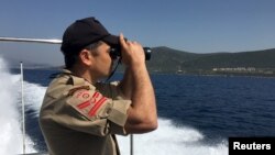 FILE - A Turkish coastguard officer looks through binoculars during a boat patrol off the Turkish coastal town of Dikili, Turkey, April 6, 2016. 