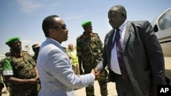 Uganda's Acting Foreign Affairs Minister Okello Oryem (R) is greeted by Somali Deputy Prime Minister and Minister for Defense Hussein Arab Issa upon his arrival at Mogadishu Airport, February 13, 2012