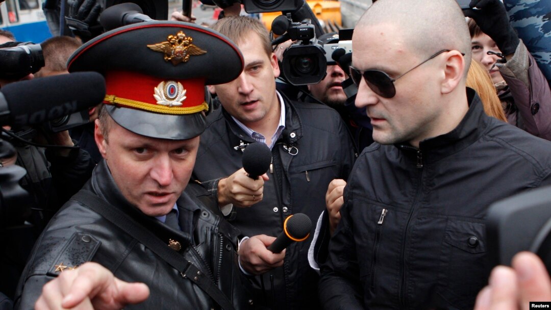 Left Front opposition movement leader Sergei Udaltsov, right, listens to a police officer as he arrives at the Investigative Committee, Moscow, Oct. 11, 2012.