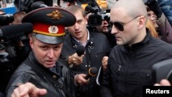 Left Front opposition movement leader Sergei Udaltsov, right, listens to a police officer as he arrives at the Investigative Committee, Moscow, Oct. 11, 2012.