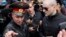 Left Front opposition movement leader Sergei Udaltsov, right, listens to a police officer as he arrives at the Investigative Committee, Moscow, Oct. 11, 2012.