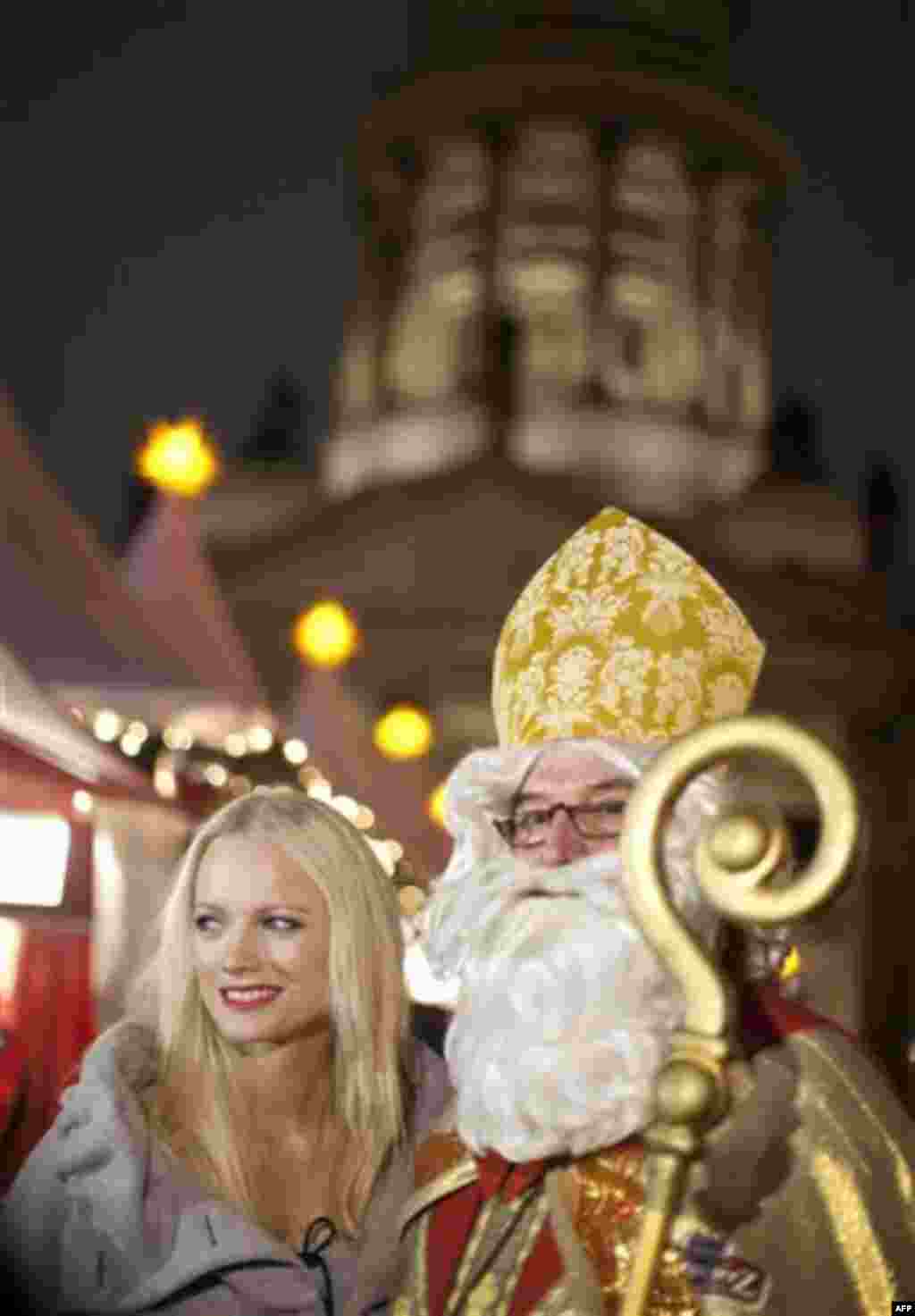 German model Franziska Knuppe, left, stands next to a man dressed as St Nicholas before the opining ceremony of the Christmas market on Gendarmenmarkt in Berlin on Monday, Nov. 22, 2010. Seen in the background is the French cathedral. (AP Photo/Gero Brelo