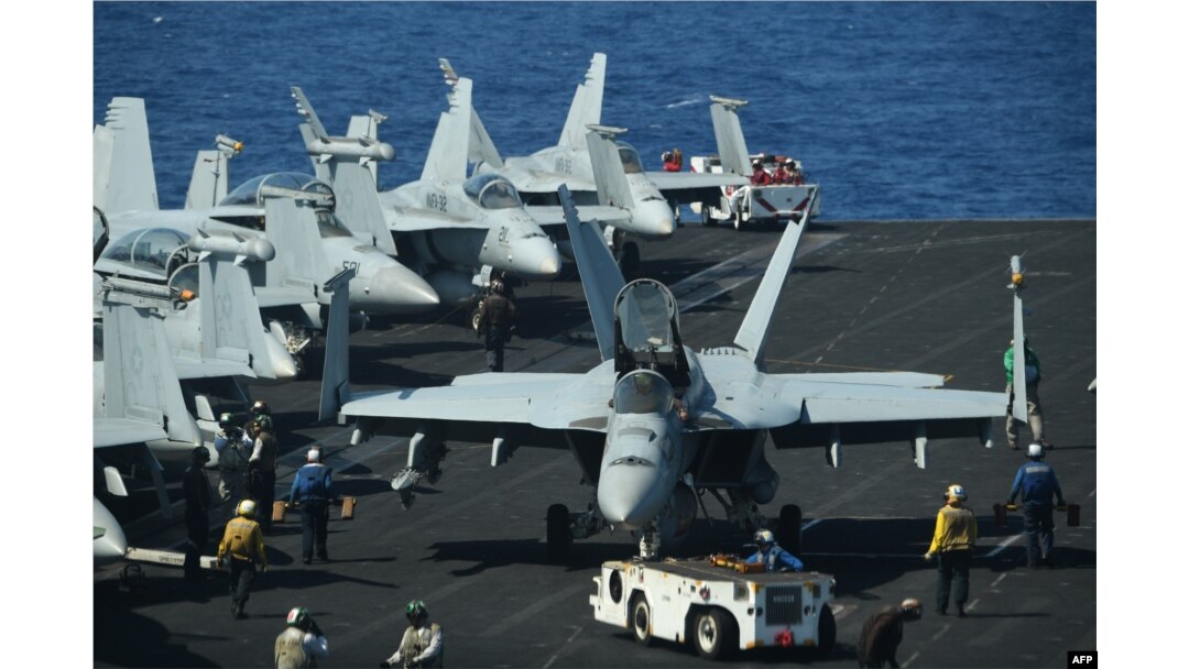 FILE - Sailors prepare FA-18 Hornet fighter jets for takeoff during routine training aboard the U.S. aircraft carrier Theodore Roosevelt in the South China Sea, April 10, 2018.