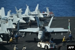 FILE - Sailors prepare FA-18 Hornet fighter jets for takeoff during routine training aboard the U.S. aircraft carrier Theodore Roosevelt in the South China Sea, April 10, 2018.