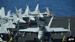 Sailors preapre FA-18 Hornet fighter jets for take off during a routine training aboard the US aircraft carrier Theodore Roosevelt in the South China sea on April 10, 2018. 
