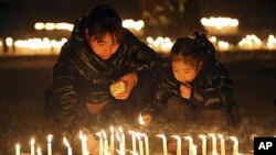 1月10號，一名男子和孩子點燃燭光悼念遇害父子