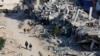 Palestinians ride a donkey-drawn cart as others walk past the rubble of houses, destroyed in previous Israeli strikes, amid the Israel-Hamas conflict, in Khan Younis, southern Gaza Strip