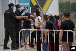Security guards help masked residents to scan their health code as they line up to receive the Sinopharm COVID-19 vaccine at the Central Business District in Beijing, June 2, 2021.