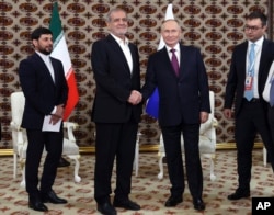 Presiden Rusia Vladimir Putin, kanan, dan Presiden Iran Masoud Pezeshkian, berjabat tangan selama pertemuan mereka di sela-sela forum internasional di Ashgabat, Turkmenistan, 11 Oktober 2024. (Foto: via AP)