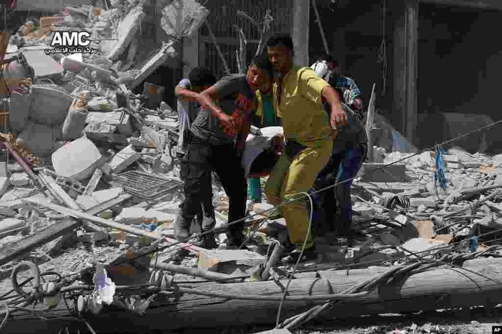 This photo provided by the Syrian anti-government activist group Aleppo Media Center (AMC), shows Syrians carrying a victim after barrel bombs were dropped on the Bab al-Nairab neighborhood in Aleppo, Aug. 27, 2016. 