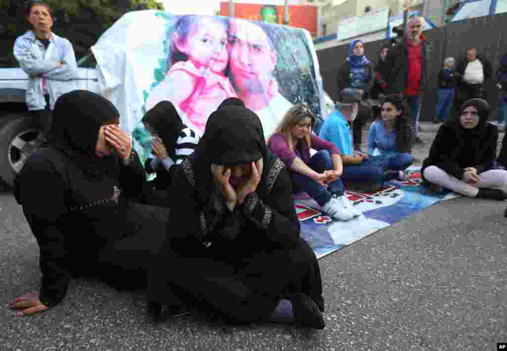 Families of Lebanese soldiers who were kidnapped by Islamic militants, block a main road during a protest after an al-Qaida-linked group in Syria says it has killed a kidnapped soldier Ali Bazzal, seen in poster with his daughter in Beirut, Lebanon, Dec. 6, 2014.