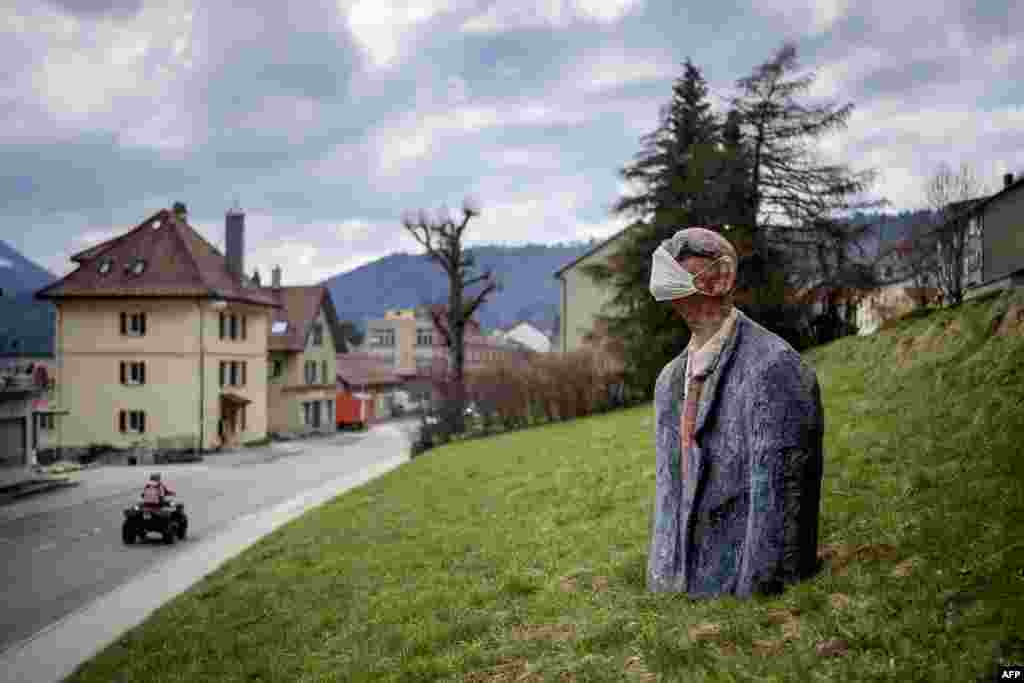 A sculpture representing a man wearing a facemask is seen as a preventive measure against the Covid-19 coronavirus in a field in Saint-Croix, Switzerland.