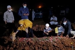 Seorang perempuan dan anak-anaknya saat pemakaman suaminya yang meninggal akibat COVID-19 di Bekasi, 27 Juli 2021. (Foto: Willy Kurniawan/Reuters)