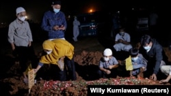 Seorang perempuan dan anak-anaknya saat pemakaman suaminya yang meninggal akibat COVID-19 di Bekasi, 27 Juli 2021. (Foto: Willy Kurniawan/Reuters)