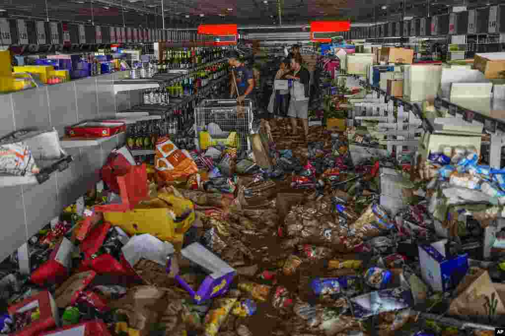 People pick up goods in a supermarket affected by the floods in Valencia, Spain.