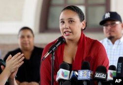 Mia Irizarry speaks at a news conference in Chicago, July 13, 2018, about an incident where a man confronted her about a T-shirt she wore emblazoned with the Puerto Rican flag at a Chicago forest preserve on June 14. Irizarry says a forest preserve police officer who appeared to ignore her pleas for help only intervened to tell someone else to "calm down." The man who confronted her has been charged with a hate crime and the officer has quit his job.