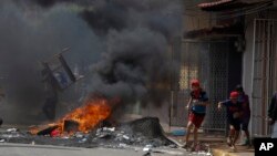 Manifestantes corren frente a una barricada ardiendo mientas se enfrentan a la policía antidisturbios y partidarios del gobierno en el distrito de Masaya, Nicaragua, el sábado, 12 de mayo, de 2018.