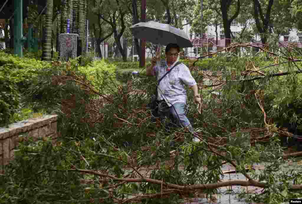 Seorang pria berjalan di antara ranting-ranting pohon yang jatuh dan memenuhi jalanan di Hong Kong akibat Topan Usagi (23/9). (Reuters/Bobby Yip)