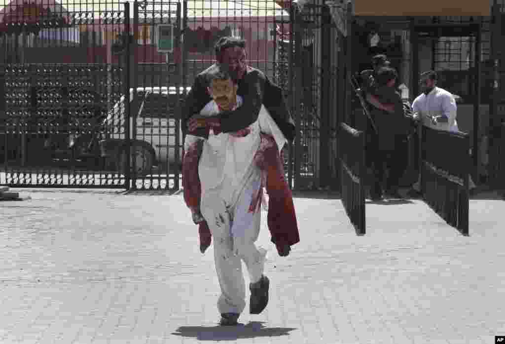 A man carries a wounded person after a suicide bombing attack on a court complex in Peshawar, March 18, 2013.