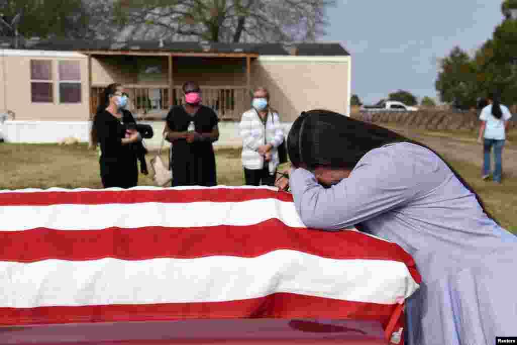 Lila Blanks holds the casket of her husband, Gregory Blanks, 50, who died of the COVID-19, ahead of his funeral in San Felipe, Texas, Jan. 26, 2021.