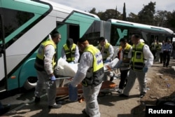 Members of Zaka Rescue and Recovery team carry a covered body from the scene of an attack on a Jerusalem bus, Oct. 13, 2015.