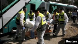 Members of Zaka Rescue and Recovery team carry a covered body from the scene of an attack on a bus in Jerusalem, Oct. 13, 2015.