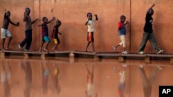 Des enfants traversent les eaux de crues sur des planches à Niamey, Niger, 2 août 2009.