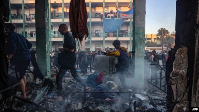 Displaced Palestinians walk amid the debris following an Israeli strike that hit a U.N.-run school where people had taken refuge, in the Nusseirat refugee camp in the central Gaza Strip on Nov. 20, 2024.