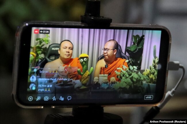 Biksu Buddha Phra Maha Sompong Talaputto dan Phra Maha Paiwan Warawanno menjadi pembawa acara obrolan selama siaran langsung Facebook, di sebuah kuil di Bangkok, Thailand, 17 September 2021. (Foto: REUTERS/Arthon Pookasook)