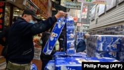 Orang-orang membeli tisu toilet yang ditumpuk di luar sebuah toko di distrik Tsuen Wan, Hong Kong, 8 Februari 2020. (Foto: Philip Fong/AFP)