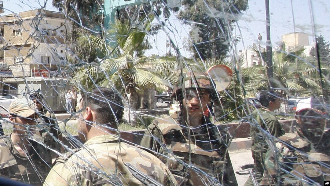 Syrian army soldiers, are seen through a damaged military truck window which was attacked by a roadside bomb, in Daraa city, southern Syria. The explosion targeted the Syrian military truck just seconds after a team of U.N. observers passed by.