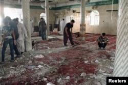 FILE - People examine the debris after a suicide bomb attack at the Imam Ali mosque in the village of al-Qadeeh in the eastern province of Gatif, Saudi Arabia, May 22, 2015.