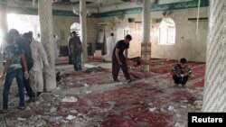 FILE - People examine the debris after a suicide bomb attack at the Imam Ali mosque in the village of al-Qadeeh in the eastern province of Gatif, Saudi Arabia, May 22, 2015.