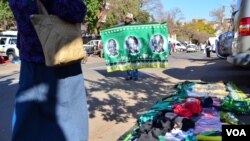 Collin Nkadimeng, left, barters with a customer Tuesday outside of the Medi-Clinic Heart Hospital in Pretoria, where former South African President Nelson Mandela has been treated since June 8. (Photo: Peter Cox / VOA)