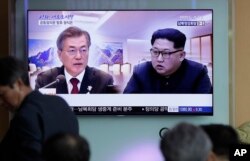 People watch a TV screen showing file footage of South Korean President Moon Jae-in and North Korean leader Kim Jong Un during a news program ahead of the inter-Korean summit at the Seoul Railway Station in Seoul, South Korea, April 26, 2018.