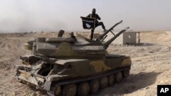 FILE - An Islamic State militant holds the group's flag as he stands on a tank captured from Syrian government forces, in the town of al-Qaryatayn southwest of Palmyra, central Syria.