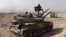 FILE - An Islamic State militant holds the group's flag as he stands on a tank captured from Syrian government forces, in the town of al-Qaryatayn southwest of Palmyra, central Syria. 