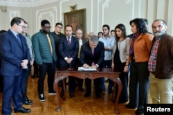 Colombian President Ivan Duque signs the financing agreement for public education accompanied by the student leaders in the presidential palace of Bogota, Colombia, Dec. 14, 2018.