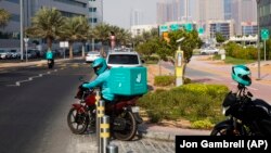 A delivery driver for the app Deliveroo prepares to make a delivery, in Dubai, United Arab Emirates, Thursday, Sept. 9, 2021. (AP Photo/Jon Gambrell)