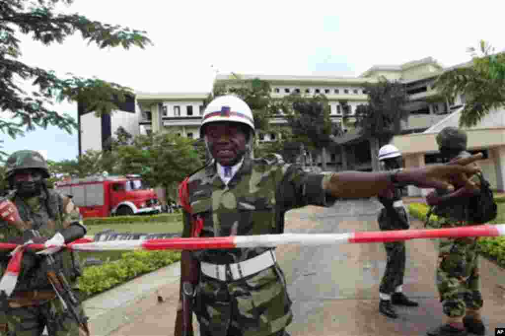 A Nigerian military policeman directs U.N. workers to another entrance, as he stands guard where a day earlier a suicide bomber crashed through an exit gate and detonated a car full of explosives in the reception area of U.N. headquarters, in Abuja, Niger