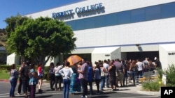 FILE - Students wait outside Everest College in Industry, Calif., hoping to get information on loan forgiveness, April 28, 2015. Everest was a part of Corinthian Colleges, which shut its U.S. campuses in April 2015, displacing 16,000 students.