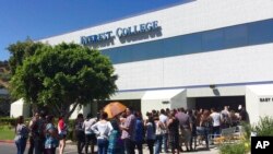 FILE - Students wait outside Everest College in Industry, Calif., hoping to get information on loan forgiveness, April 28, 2015. Everest was a part of Corinthian Colleges, which shut its U.S. campuses in April 2015, displacing 16,000 students.