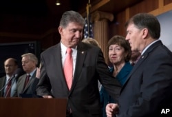 Sen. Joe Manchin, D-W.Va. (C), Sen. Susan Collins, R-Maine, and Sen. Mike Rounds, R-S.D., join others in their "common sense coalition" to discuss the bipartisan immigration deal they reached with other centrists this week that sought to offer citizenship to young "Dreamer" immigrants with President Donald Trump's demands for billions to build a border wall with Mexico, during a news conference at the Capitol in Washington, Feb. 15, 2018.