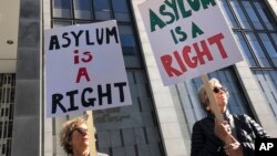 ARCHIVO - Manifestantes sostienen carteles en inglés que dicen "El asilo es un derecho" afuera del Tribunal Federal de San Francisco, el 24 de julio de 2019, en San Francisco, EEUU.