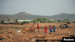 FILE - Residents walk past Adi Harush Refugee camp in Mai Tsberi town in Tigray Region, Ethiopia, June 26, 2021.